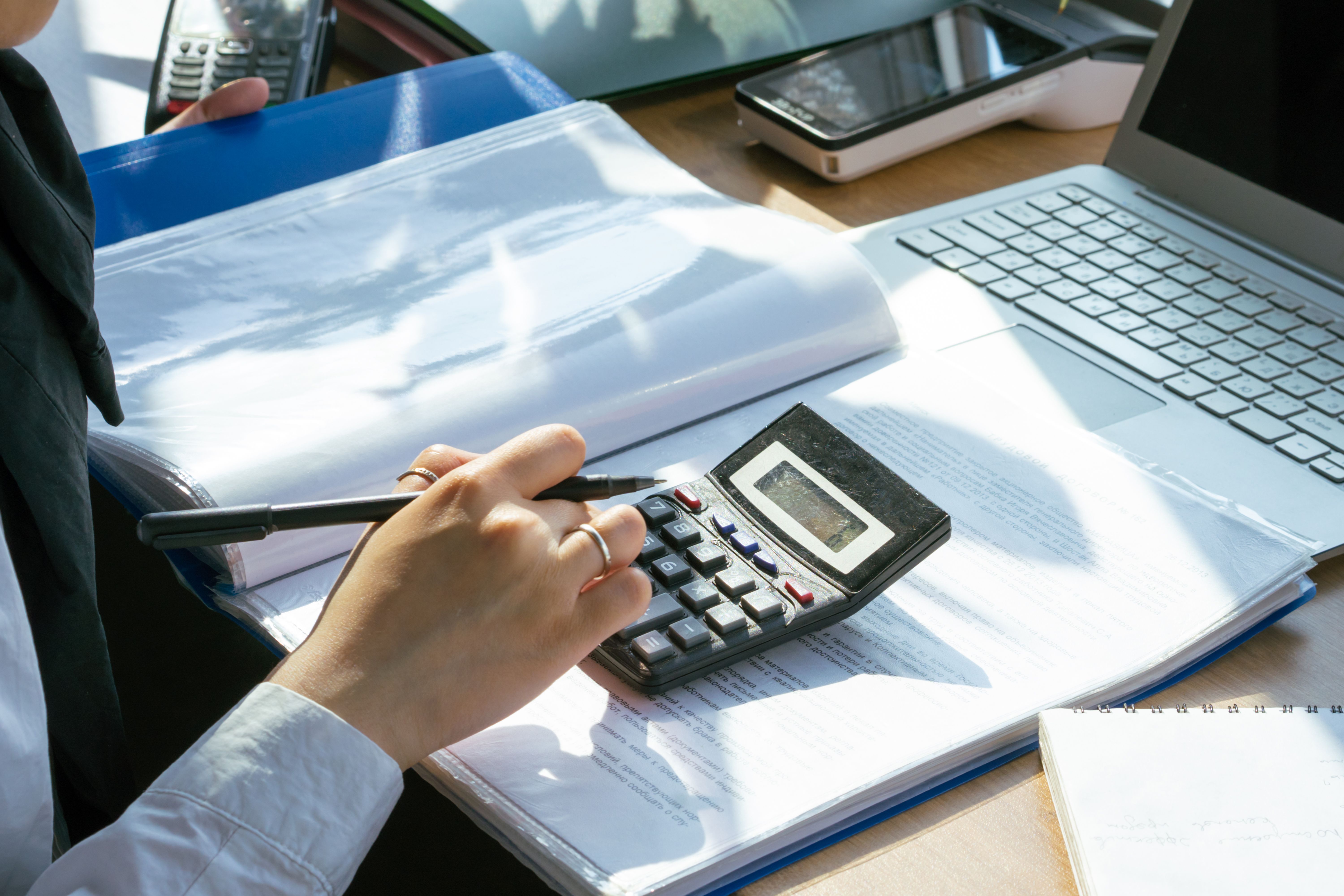 Tax preparation documents, calculator, and laptop on a desk