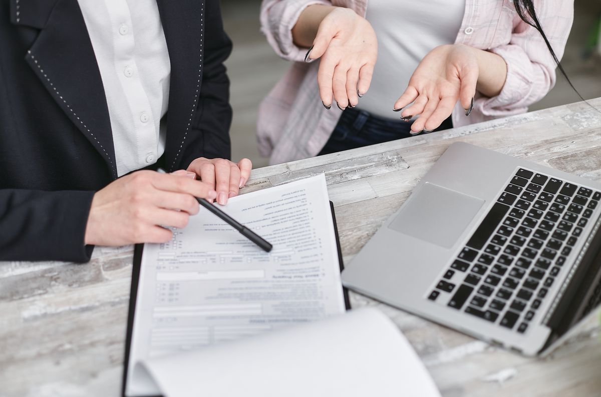 Two professionals discussing a contract beside a laptop