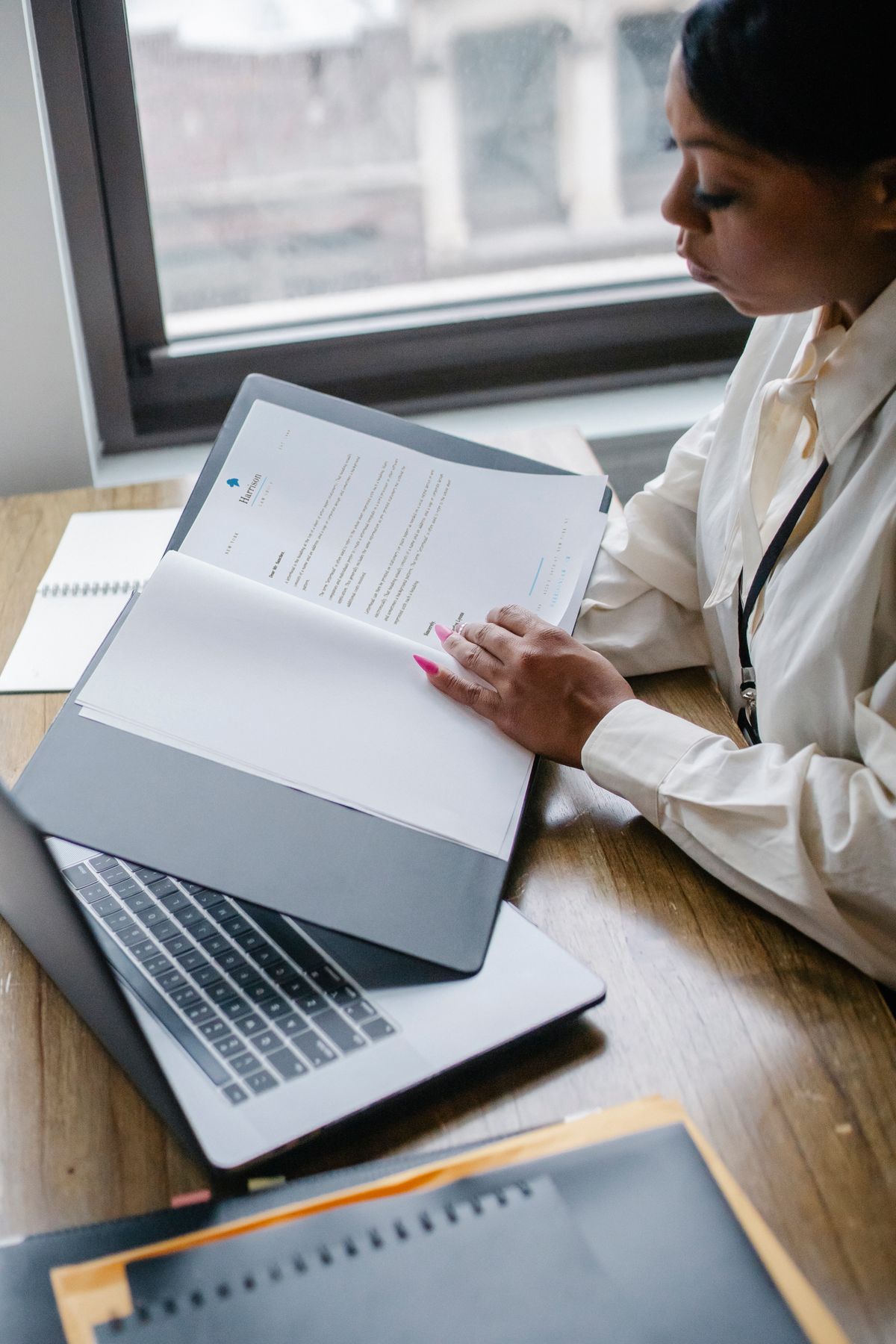 Professional reviewing business documents beside an open laptop