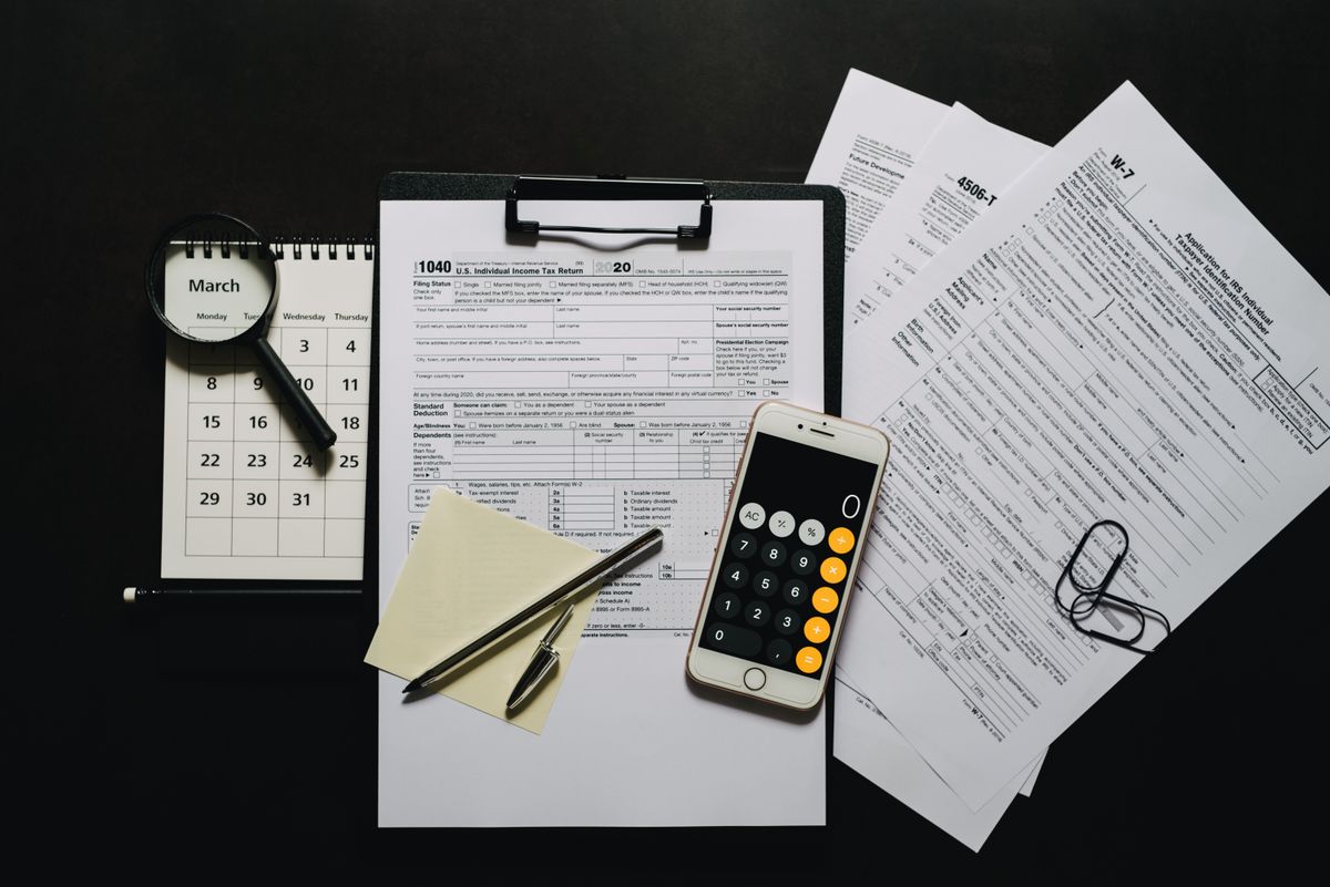 Tax forms, a calculator phone, and planning tools arranged on a desk